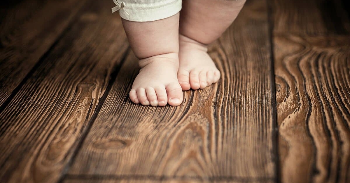 Kinderfüße auf dunklem Dielenboden