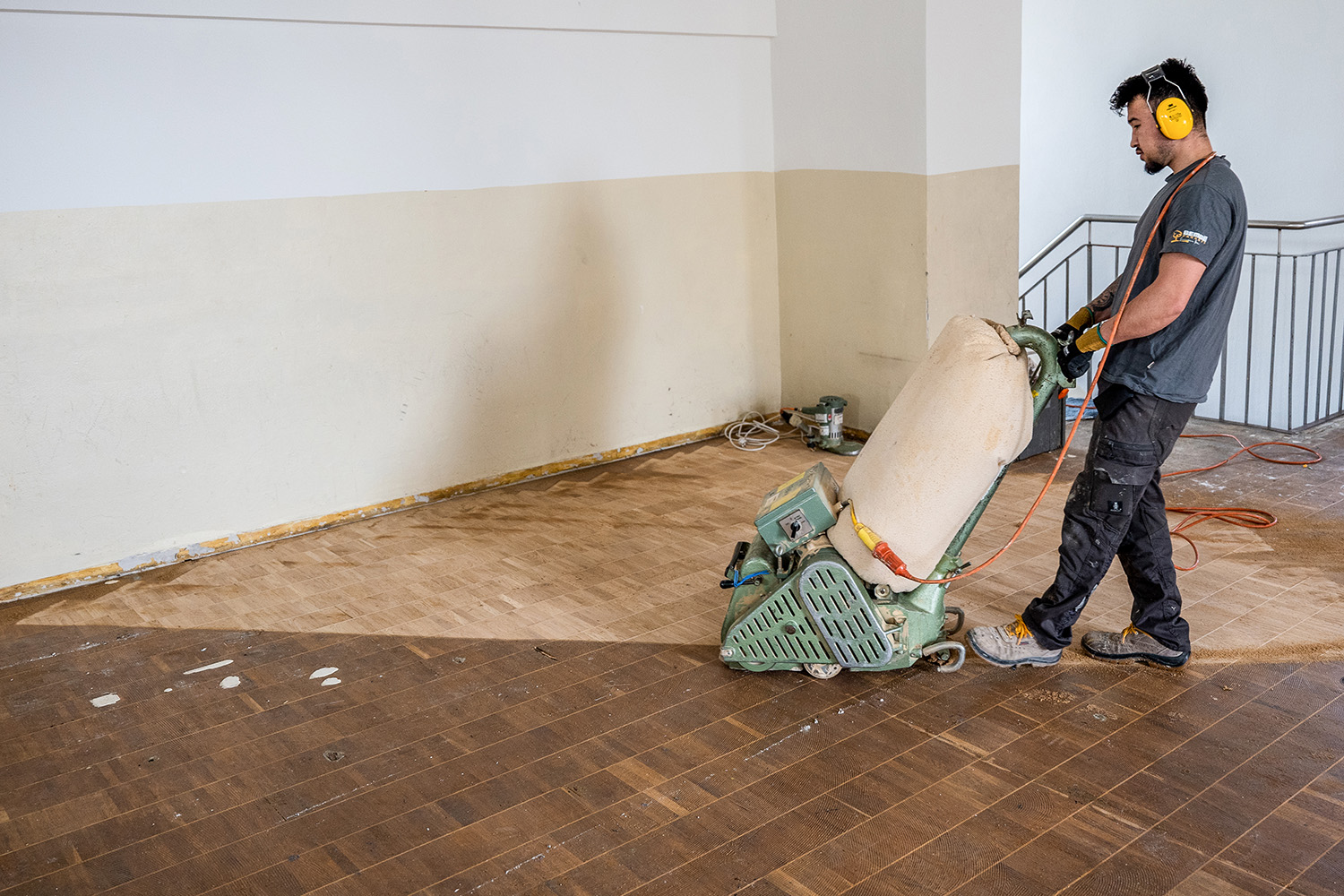 Konzentrierter Parkettleger schleift in Turnhalle Eppingen