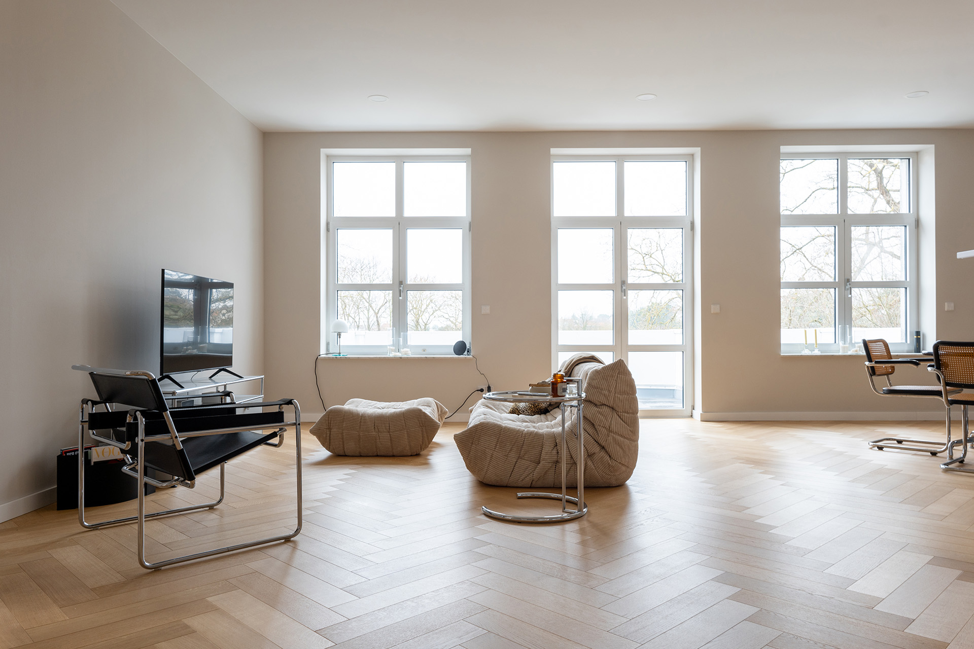 Comfort Tabis XL als Fischgrat verlegt mit ruhiger Sortierung in heller Wohnung mit Stuhl, beiger Couch und Fernseher