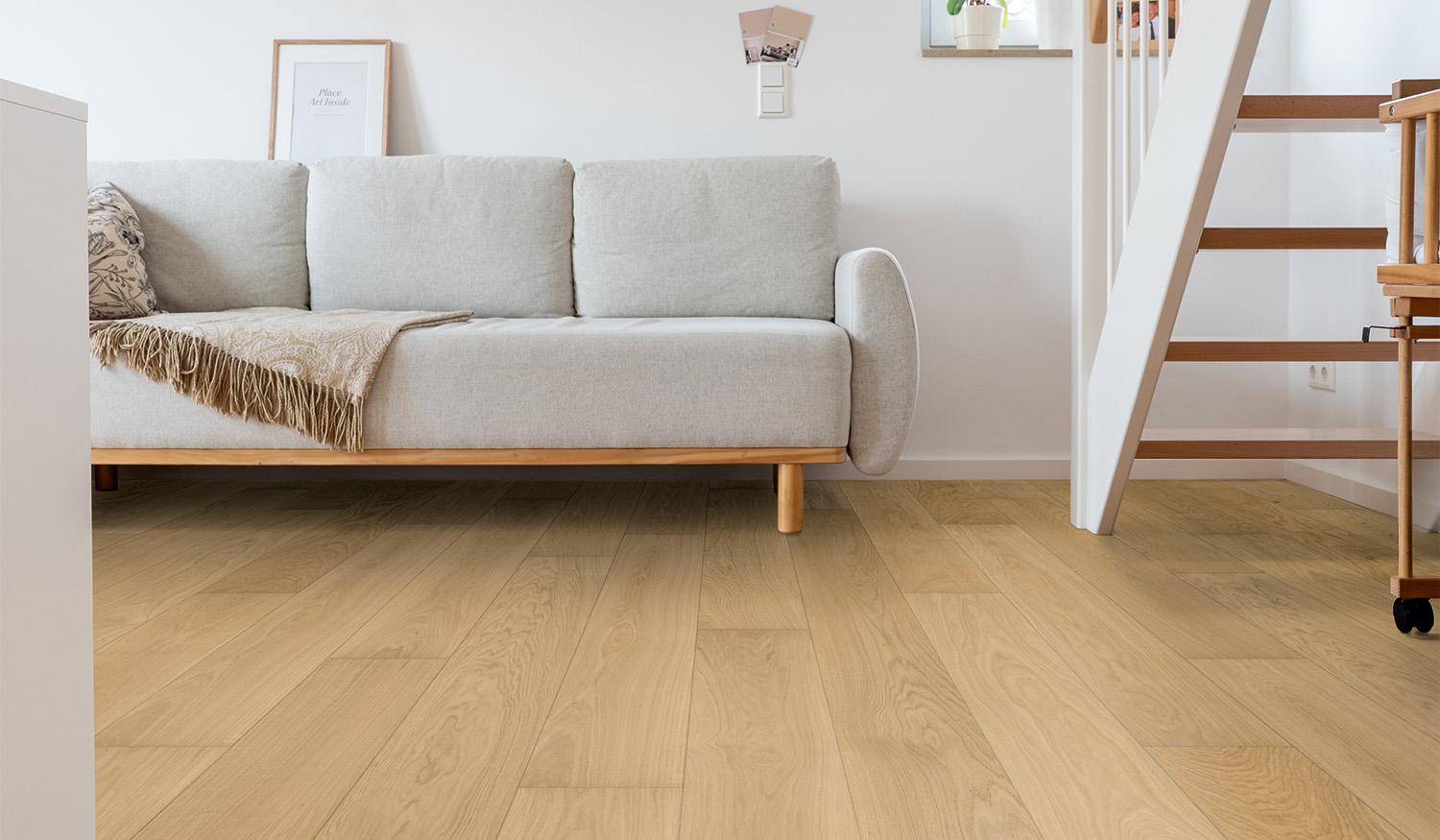 Wohnzimmer mit heller Landhausdiele Eiche in naturmattem Ton unter einem Sofa in skandinavischem Stil