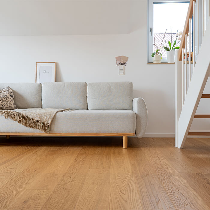 Wohnzimmer mit Dielenboden aus Eiche sowie modernen Einrichtungsgegenständen und einer hellen Couch