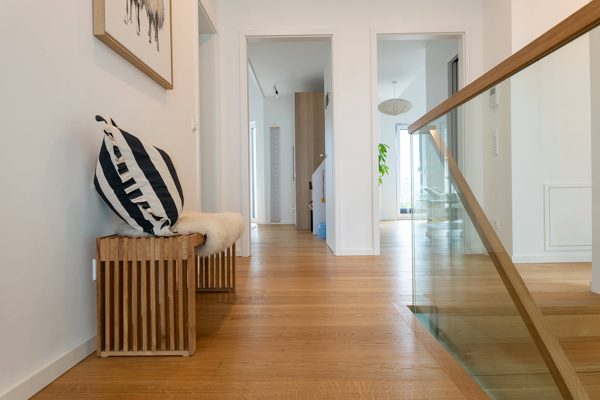 Heller Hausflur mit geöltem Dielenboden sowie moderner Einrichtung wie einer Sitzbank