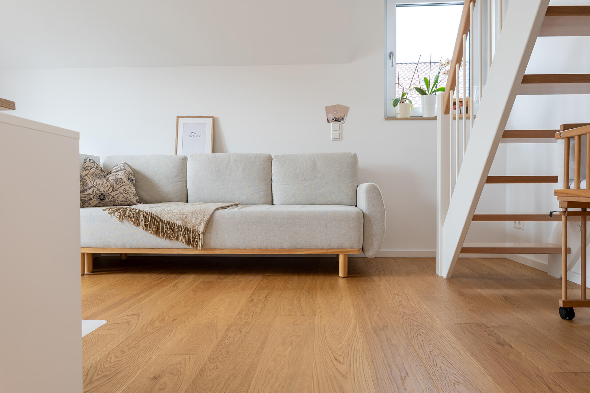 Wohnzimmer mit geölter Comfort Tabis Diele Grande sowie modernen Einrichtungsgegenständen und einer hellen Couch