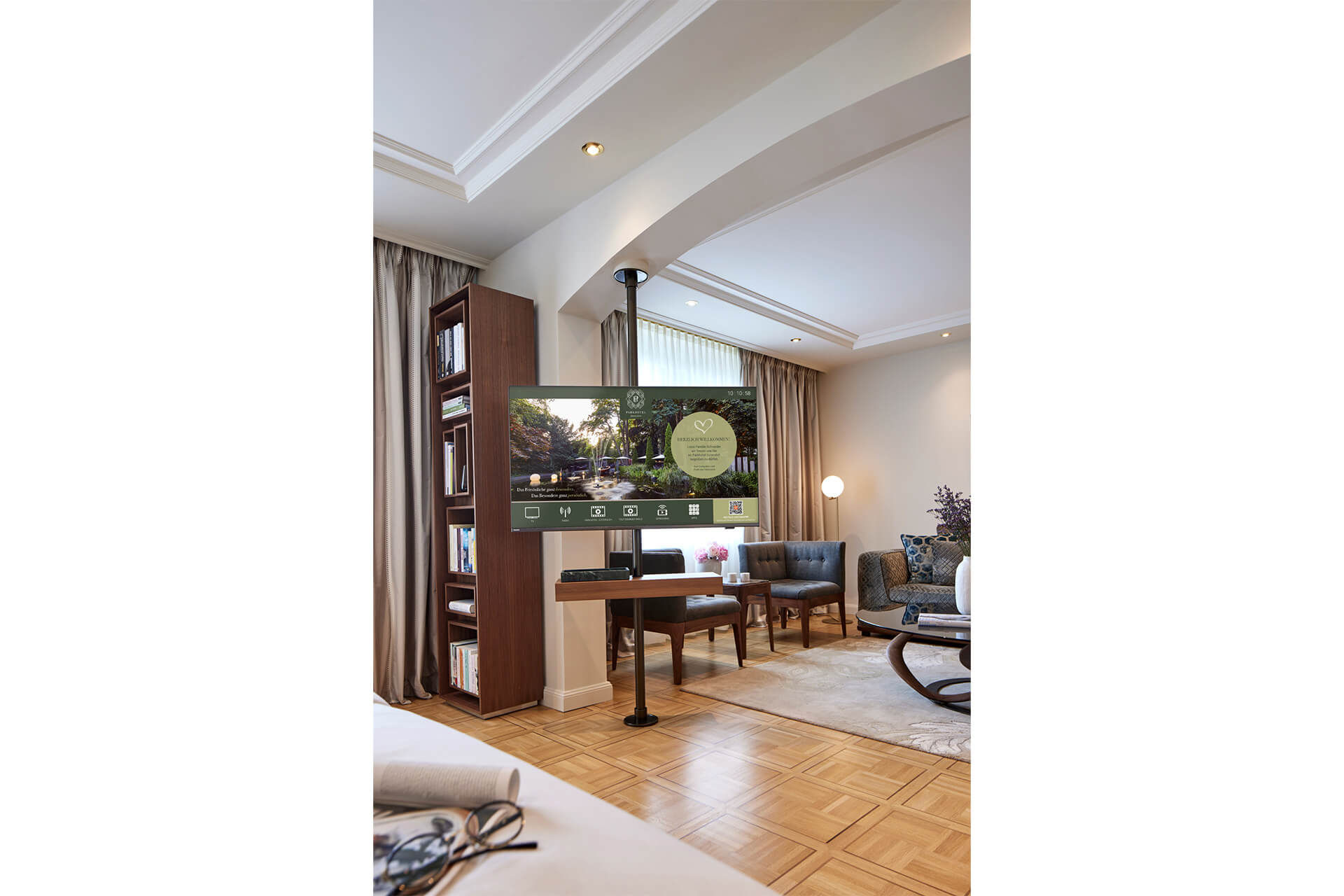 parkhotel-gütersloh-meisterparkett-eiche-ravenna-2 (1) Wohnbereich einer Suite im Parkhotel Gütersloh mit Meisterparkett Ravenna Eiche geölt, Schreibtisch, Bücherregal und gemütlicher Sitzecke