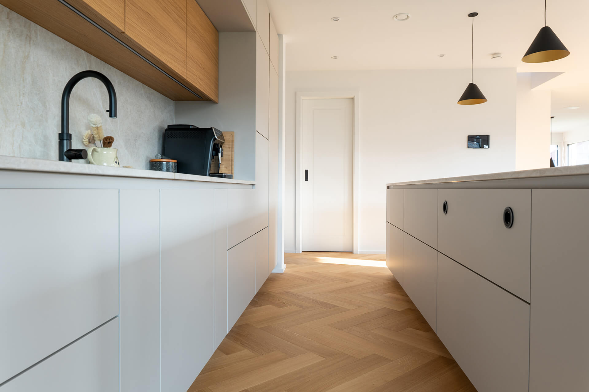 comfort-tabis-xl-eiche-elegance-geölt-fischgrat-1 Offene Küche mit Fischgrat-Parkettboden aus Eiche Elegance, grifflosen Fronten und warmen Eichenholz-Oberschränken